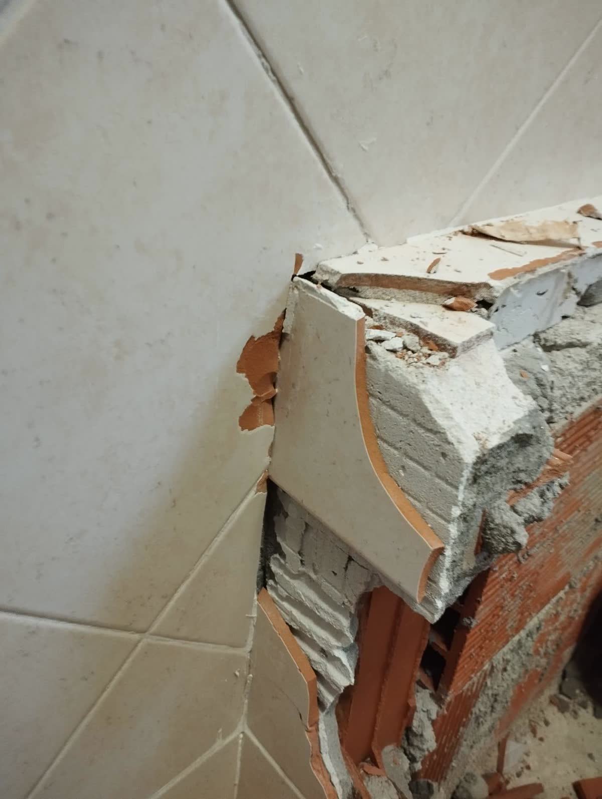 Muretto del bagno demolito con piastrelle e mattoni a vista