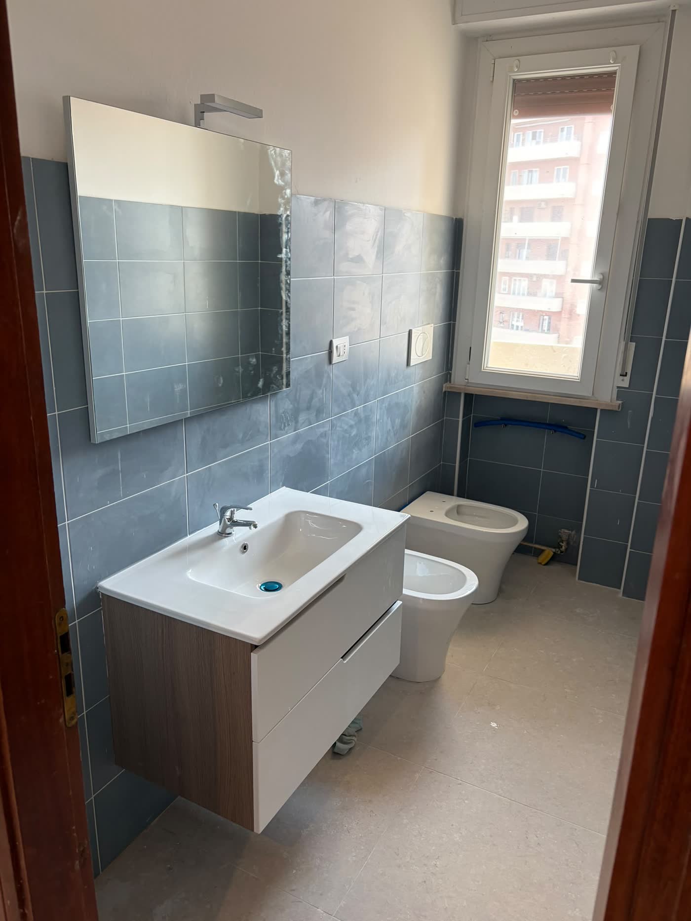 Bagno rifatto a Pesaro: rivestimento azzurro, mobile sospeso con lavabo, sanitari nuovi