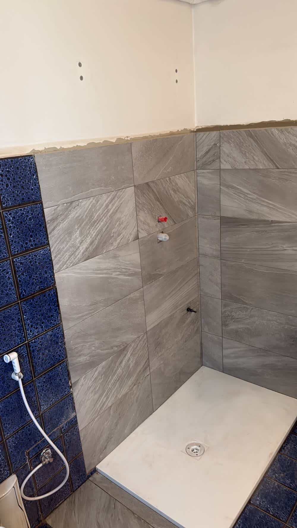 Doccia nuova con rivestimento grigio e piatto doccia a filo pavimento