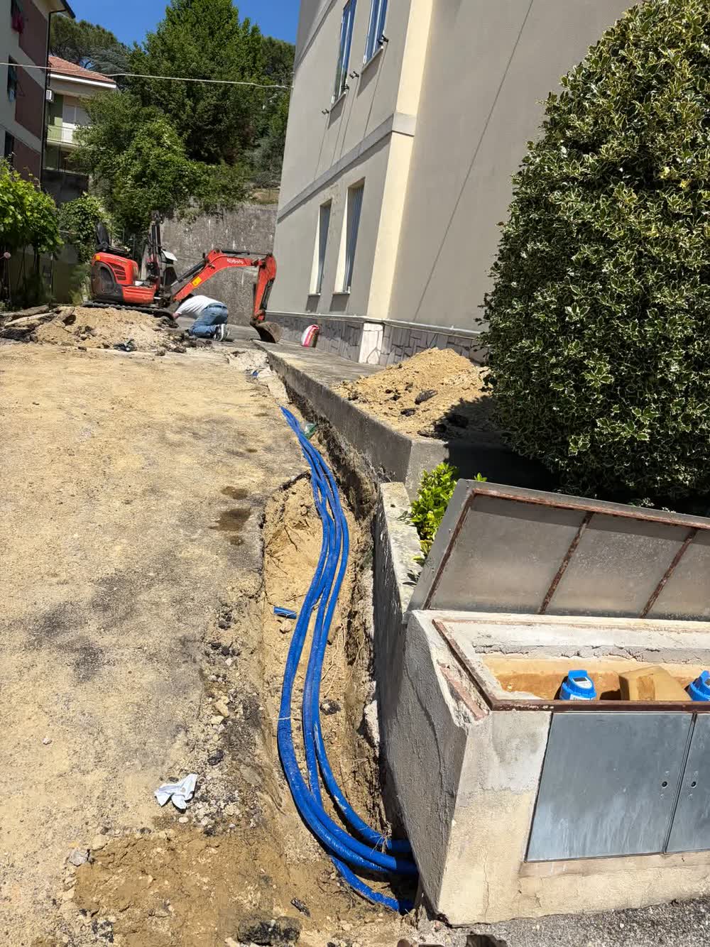 Cantiere con lo scavo aperto e i tubi dell'acqua nuovi posati fino al pozzetto dei contatori
